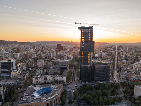 Aerial view of Downtown One skyscraper under construction with a crane on top, surrounded by the urban cityscape of Tirana, Tirana County, Albania.