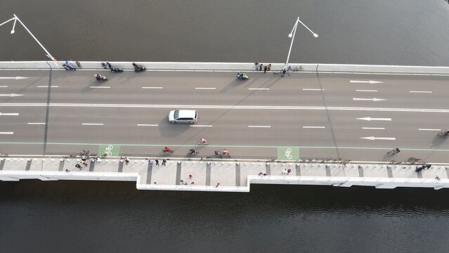 Kecamatan Penjaringan, Indonesia - 19 September 2021: Aerial view of the bridge at Golf Island in PIK with cyclists on the bike lane, pedestrians, and a car driving over the water.
