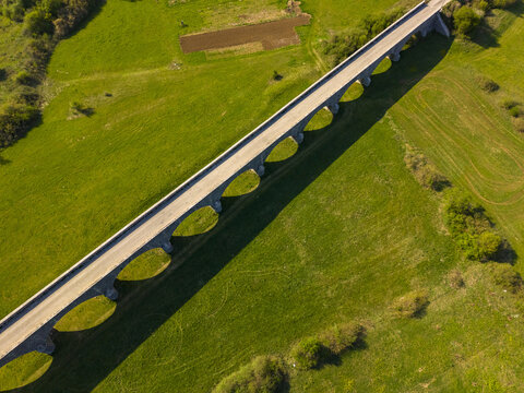 Aerial view of Tsar's Bridge, a historic stone arch bridge, spanning over green fields in the countryside in Niksic, Opstina Niksic, Montenegro.