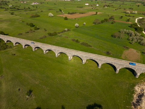 Aerial view of the historic stone Tsar's Bridge spanning across lush green fields in Niksic, Opstina Niksic, Montenegro.