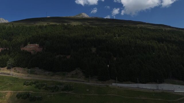 Mountain landscape static, in outdoor daytime, with mountains, trees, from a wide-angle aerial perspective, with green, blue accents, and serene mood, with nearby objects.