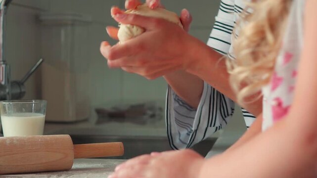 Close-up of a mother and her child's hands kneading dough on a floured countertop. Family cooking together, making bread or pizza at home