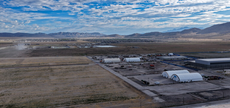 Aerial view of industrial warehouses and construction site near a data center in a desert landscape with mountains in the background in Eagle Mountain, Utah, United States.