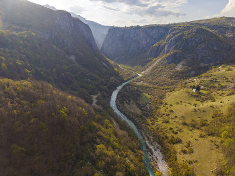 Aerial view of the winding river flowing through the deep canyon of Gradac, surrounded by lush forested slopes and rocky cliffs in Gradac, Savnik Municipality, Montenegro.