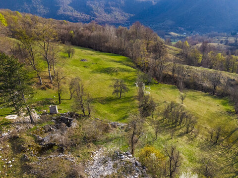Aerial view of the rural landscape of Gradac, featuring green meadows, scattered trees, and rocky terrain in the mountainous region of Gradac, Savnik Municipality, Montenegro.