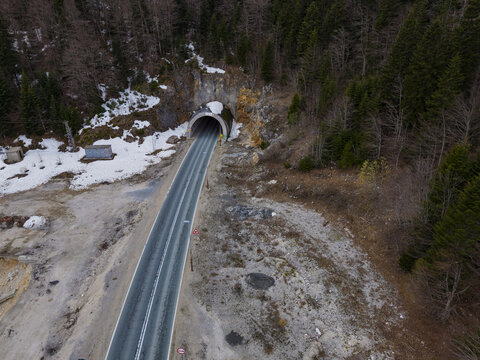 Aerial view of a road tunnel entrance in Durmitor National Park, surrounded by pine forests and patches of snow in Zabljak, Zabljak Municipality, Montenegro.