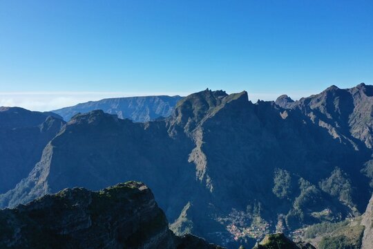 Aerial view of the rugged mountain peaks and deep valleys surrounding Miradouro da Vigia in the lush landscape of Sao Jorge, Madeira, Portugal.
