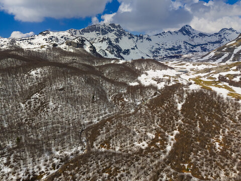 Aerial view of Durmitor National Park with snow-capped peaks, bare forests, and patches of snow in Zabljak, Zabljak Municipality, Montenegro.
