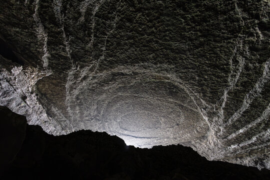 Aerial view of the massive cavern ceiling with unique circular geological formations and rugged rock textures inside the Zhijin County cave system in Bijie, Guizhou, China.