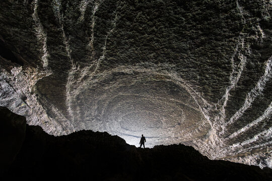 Aerial view of Zhijin Cave with a person standing inside the massive cavern with textured rock formations and dramatic lighting Bijie, Guizhou, China.