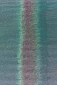 Aerial view of a distinct vertical band of algae or sediment stretching through the turquoise water in Unalaska, Alaska, United States.