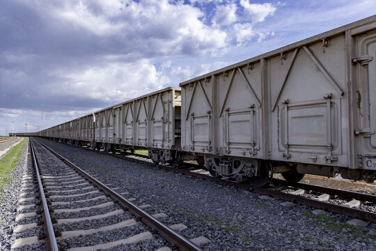 View of a long freight train with beige cargo cars on railway tracks under a cloudy sky in Nairobi, Nairobi County, Kenya.