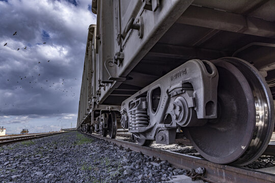 View of a heavy freight train wheel and bogie assembly resting on steel tracks under a dramatic cloudy sky in Nairobi, Nairobi County, Kenya.