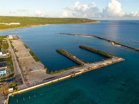 Aerial view of Tinian Port and marina with concrete piers extending into the calm turquoise water of the bay in San Jose, Tinian, Northern Mariana Islands.
