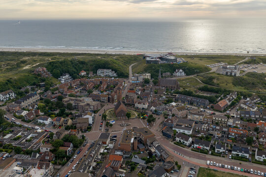 Aerial view of Wijk aan Zee with its historic church, dense residential rooftops, and surrounding dunes leading to the North Sea coastline in Wijk aan Zee, North Holland, Netherlands.