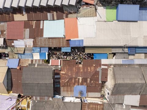 Aerial view of Maeklong Railway Market with colorful metal rooftops, crowded market stalls, and narrow railway tracks in Mae Klong, Samut Songkhram, Thailand.