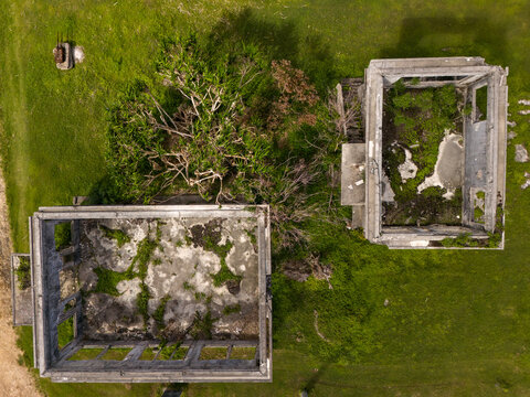 Aerial view of the ruins of the Old Japanese Sugar Company HQ with overgrown vegetation and concrete walls in San Jose, Tinian, Northern Mariana Islands.