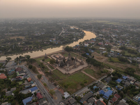 Aerial view of the historic Wat Chaiwatthanaram temple complex along the river, surrounded by greenery and the urban landscape of Tambon Ban Pom, Chang Wat Phra Nakhon, Thailand.