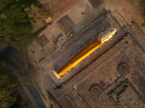 Aerial view of Wat Lokaya Sutha with its reclining Buddha statue draped in a saffron robe amidst ancient brick ruins in Phra Nakhon Si Ayutthaya District, Phra Nakhon Si Ayutth, Thailand.