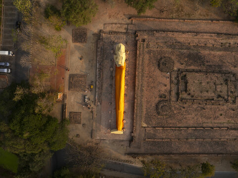 Aerial view of the reclining Buddha statue at Wat Lokaya Sutha, surrounded by ancient brick ruins and lush trees in Phra Nakhon Si Ayutthaya District, Phra Nakhon Si Ayutth, Thailand.