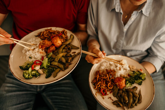 Couple enjoying asian takeout dinner with chopsticks