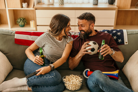 Happy couple cheering soccer match at home