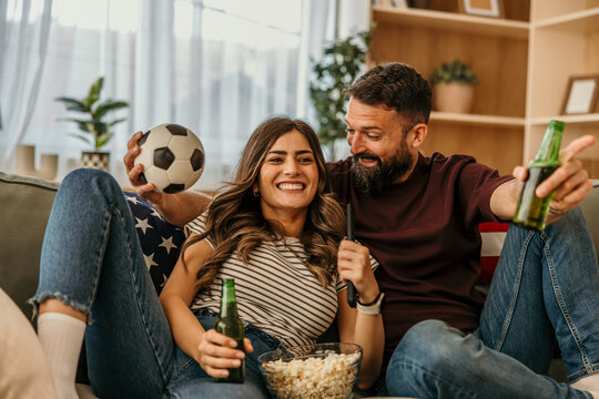 Happy couple cheering soccer match watching tv at home