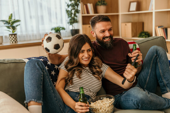 Happy couple watching soccer at home cheering for team