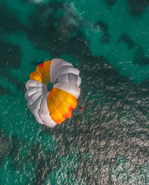 Aerial view of a parasail with a colorful canopy gliding over the clear turquoise waters of the Caribbean Sea in Punta Cana, La Altagracia Provinc, Dominican Republic.