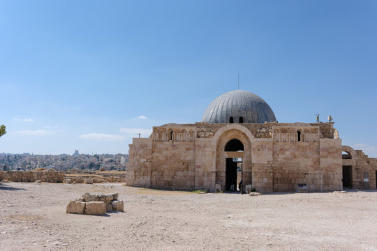 View of the Umayyad Palace with its iconic dome and stone facade, set against a clear blue sky in the historic citadel area of Amman, Amman Governorate, Jordan.