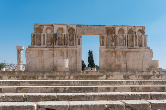View of the Umayyad Palace ruins, featuring an ornate stone gateway with intricate carvings under a clear blue sky in Amman, Amman Governorate, Jordan.