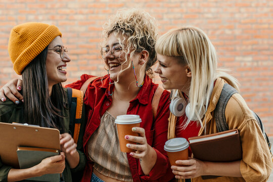 Diverse students laughing sharing coffee on campus