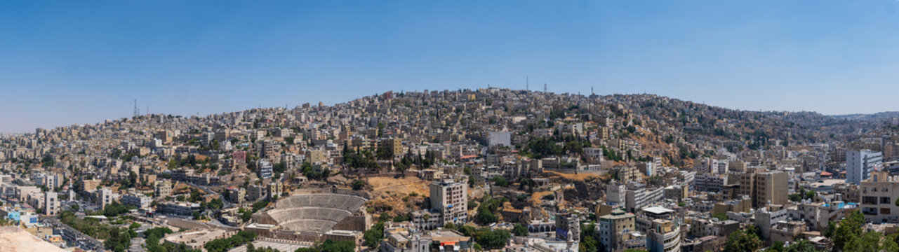 View of the historic Roman Theatre nestled among the dense urban landscape and hills of Amman, Amman Governorate, Jordan.