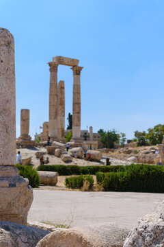 View of the ancient Temple of Hercules columns at the Amman Citadel, with historic ruins and visitors under a clear blue sky in Amman, Amman Governorate, Jordan.