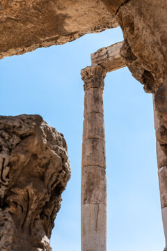 View of the ancient stone columns of the Amman Citadel framed by weathered rock formations under a clear blue sky in Amman, Amman Governorate, Jordan.