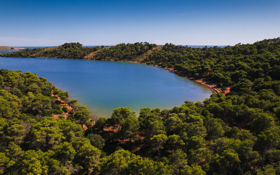 Aerial view of Telascica Nature Park featuring a serene bay surrounded by dense pine forests and rocky terrain in Sali, Zadar County, Croatia.