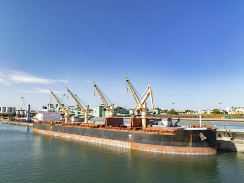 Aerial view of a large cargo ship docked at Kilindini Harbour with cranes and industrial infrastructure under a clear blue sky in Mombasa, Kwale County, Kenya.