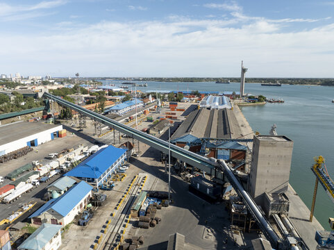 Aerial view of Kilindini Harbour featuring industrial conveyor belt systems, shipping containers, and warehouses along the waterfront in Mombasa, Kwale County, Kenya.