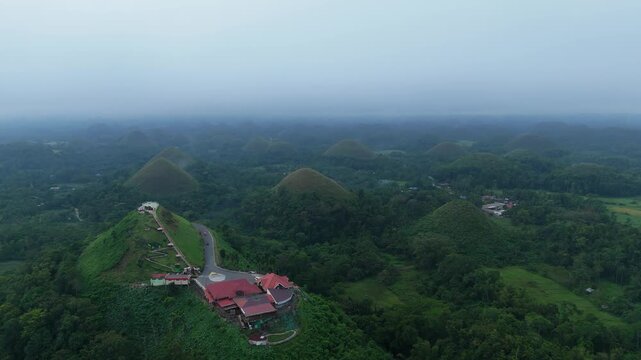 Aerial view of the iconic Chocolate Hills landscape with lush green mounds and a viewing deck in Carmen, Bohol, Philippines.