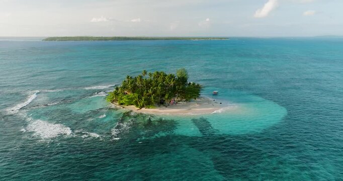 Aerial view of Guyam Island surrounded by turquoise water and palm trees in General Luna, Caraga, Philippines.