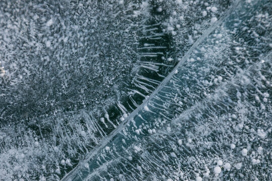 View of Lake Baikal's frozen surface with intricate ice cracks and trapped methane bubbles in Khuzhir, Irkutsk Oblast, Russia.