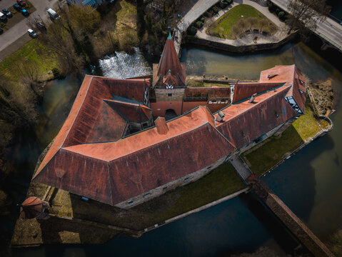 Aerial view of the historic Wenzelschloss castle surrounded by a moat with red tiled roofs and stone walls in Lauf an der Pegnitz, Bavaria, Germany.