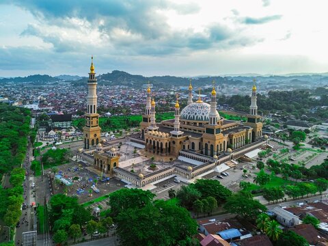 Aerial view of Baitul Muttaqien Mosque, the East Kalimantan Islamic Center, with its grand dome and towers surrounded by urban streets and greenery in Samarinda, Kalimantan Timur, Indonesia.