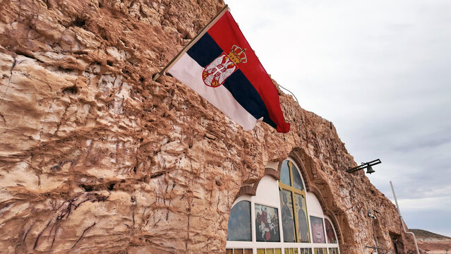 Coober Pedy, South Australia, Australia - 15 January 2025: View of the Serbian Orthodox Church carved into the sandstone rock face with a Serbian flag flying above the entrance.