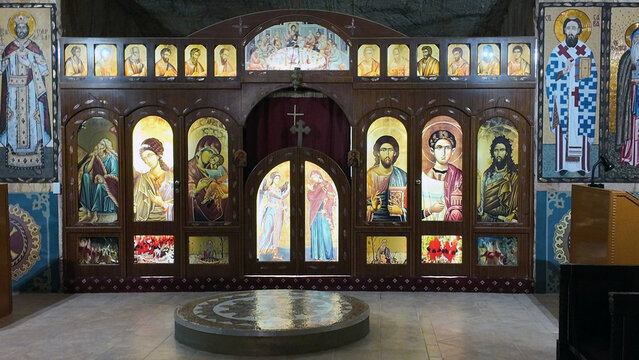Coober Pedy, Australia - 15 January 2025: View of the underground Serbian Orthodox Church interior featuring an ornate wooden iconostasis with illuminated religious icons.