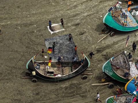 Cox's Bazar, Bangladesh - 10 April 2026: Aerial view of Cox's Bazar Sea Beach with fishermen sorting their catch on the sand beside traditional wooden fishing boats.