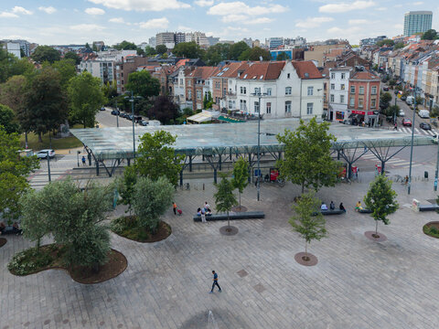 Ixelles, Belgium - 03 July 2026: Aerial view of Place Eugene Flagey featuring its modern glass canopy, surrounding historic townhouses, paved square with trees, and people walking.