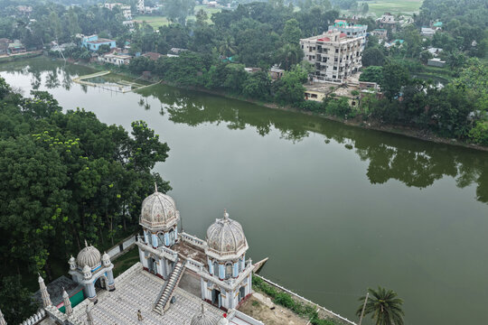 Dhanbari Upazila, Bangladesh - 15 June 2026: Aerial view of the historic Dhanbari Nawab Bari Mosque complex with ornate domes and a large pond surrounded by lush trees and buildings.