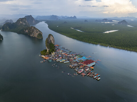 Aerial view of Ko Panyi, a floating fishing village built on stilts, surrounded by limestone karst formations and lush mangrove forests in Ko Panyi, Phang Nga, Thailand.