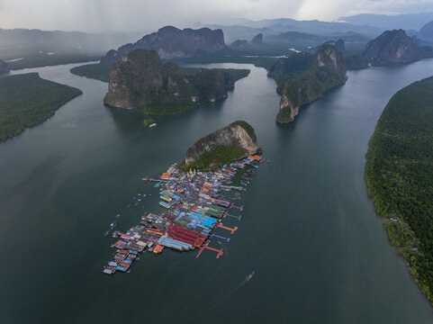 Aerial view of Ko Panyi floating village built on stilts over the water surrounded by limestone karst formations and lush mangrove forests in Ko Panyi, Phang Nga, Thailand.